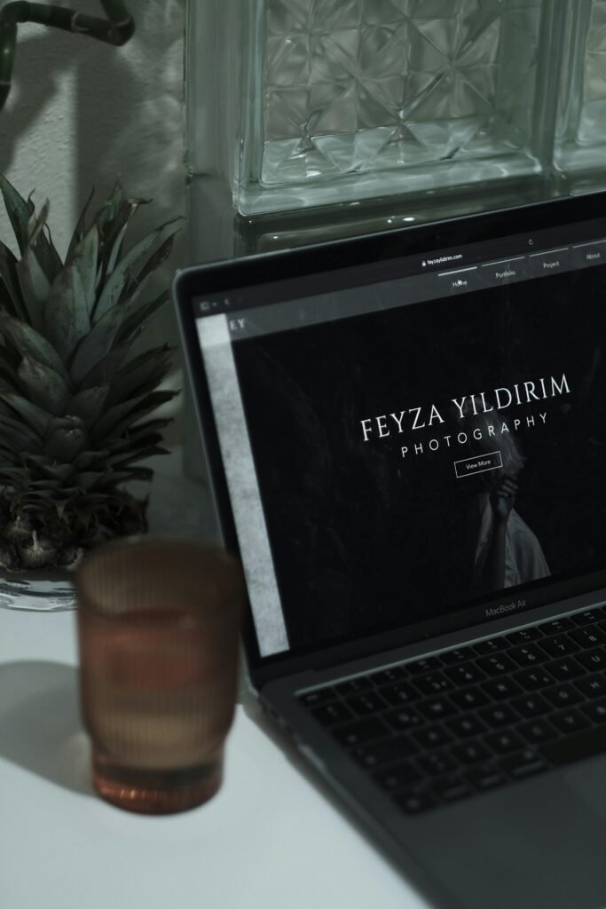 An aesthetically pleasing workspace featuring a laptop with a photographer's website, surrounded by minimalist decor.