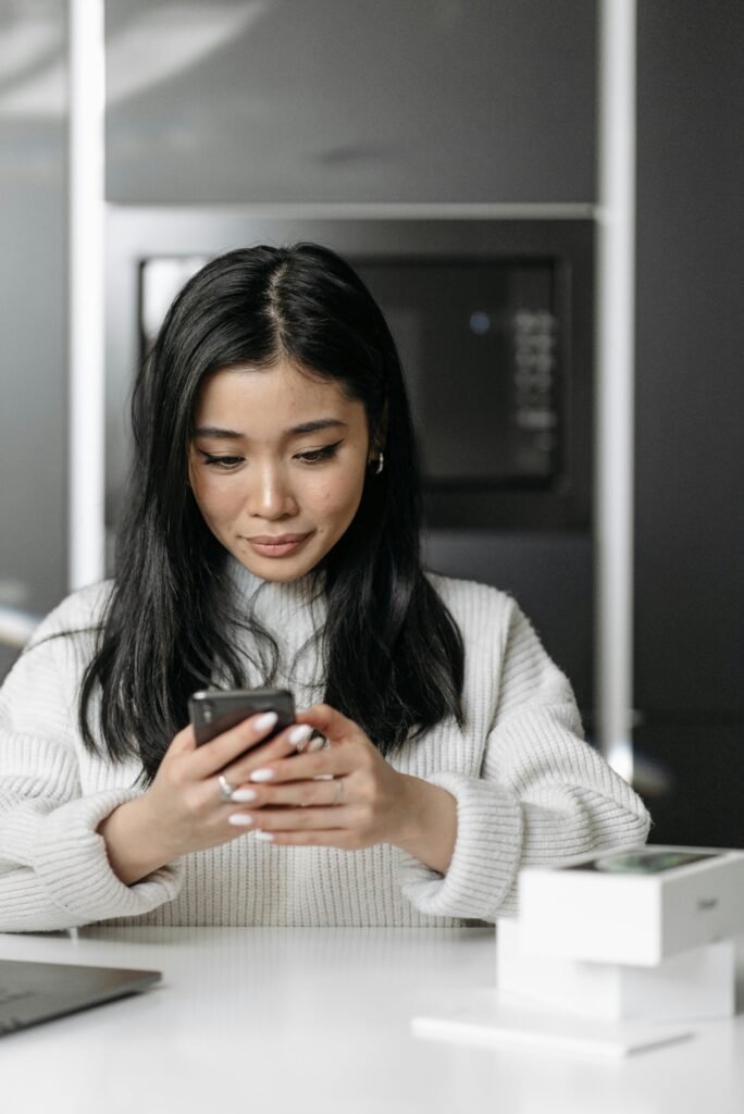 Young woman unpacking and using a new smartphone indoors.